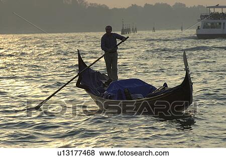 Oarsman driving a gondola in a canal in Venice, Italy View Large Photo Image Stock Photo - Oarsman driving a gondola in a canal in Venice, Italy. Fotosearch