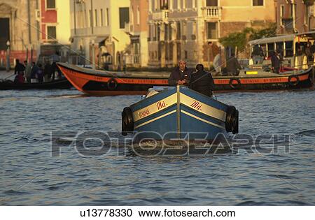 Stock Image - People traveling by motor boat in a canal in Venice, Italy. Fotosearch