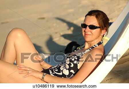 Close-up of a young woman wearing a swim suit relaxing on a deck chair on a beach View Large Photo Image Stock Photo - Close-up of a young woman wearing a swim suit relaxing on a deck chair on a beach. Fotosearch