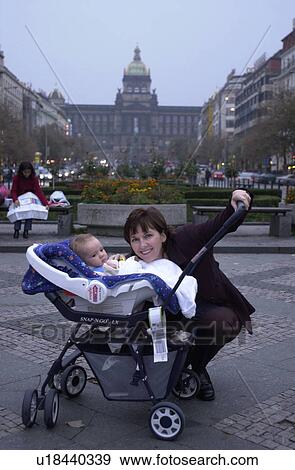 Stock Photo - Portrait of woman holding a pram with a baby in Prague. Fotosearch