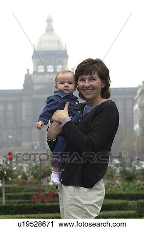 Stock Image - Portrait of young woman holding baby in Prague. Fotosearch
