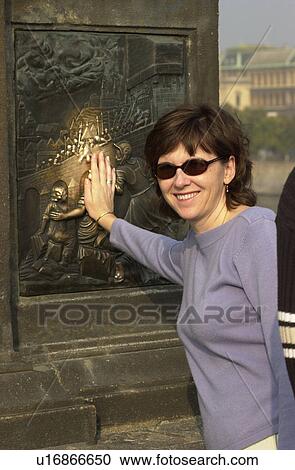 Stock Image - Portrait of young woman touching a sculpture in Prague. Fotosearch
