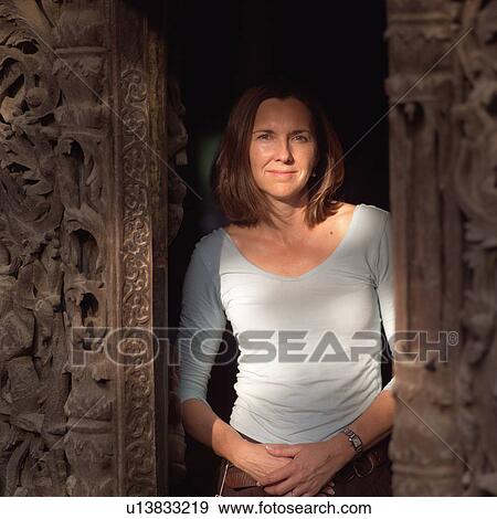 Stock Photo - Woman standing in wall opening at Buddhist Monastery. Fotosearch