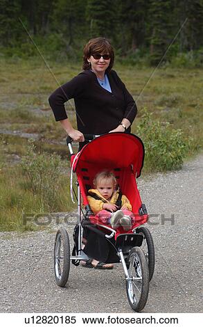 young woman holding a pram with a bab View Large Photo Image Stock Photography - young woman holding a pram with a bab. Fotosearch