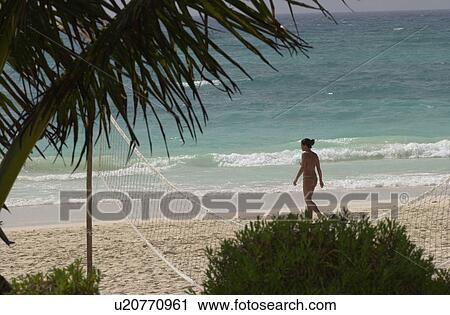 Stock Image - Young woman walking on the beach in Mexico. Fotosearch