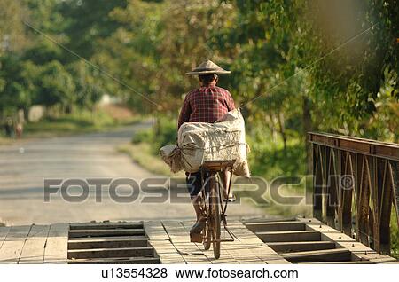 Stock Photo - Burmese man riding away on a bike. Fotosearch