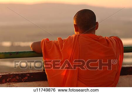 Stock Photograph - Monk looking out on Mandalay sunset. Fotosearch
