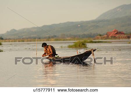 Stock Image - Boy crouching in boat. Fotosearch