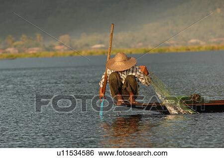 Stock Photograph - Fisherman crouching in boat. Fotosearch