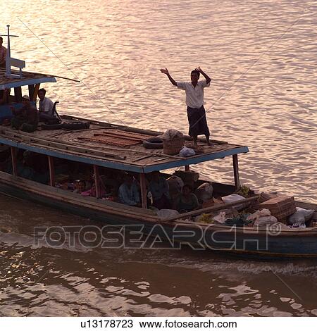 Stock Image - Man standing on boat on Ayevanwady River. Fotosearch