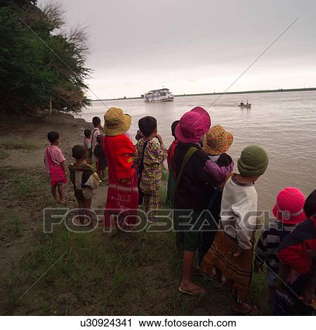 Stock Image - People standing on the shoreline of the Ayevanwady River. Fotosearch