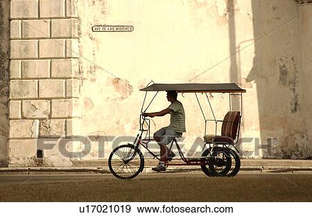 Stock Photo - A man riding a pedicab, Havana, Cuba. Fotosearch