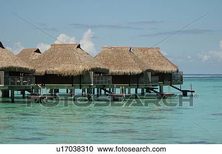 Stock Image - Thatched buildings on stilts built in the sea, Moorea, Tahiti, French Polynesia, South Pacific. Fotosearch