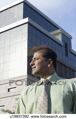 Stock Image - Businessman standing in front of a building. Fotosearch