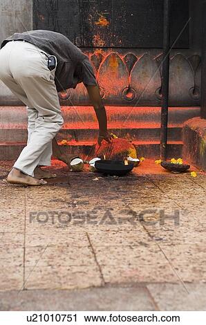 Stock Image - Rear view of a man applying sindoor on a rock, Tirupati, Tirumala Venkateswara Temple, Tirumala, Andhra Pradesh, India. Fotosearch