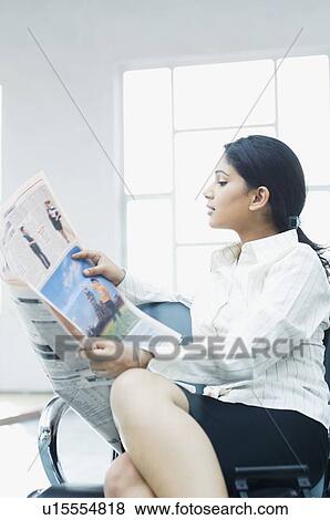 Businesswoman sitting at an airport and reading a newspaper View Large Photo Image Stock Photo - Businesswoman sitting at an airport and reading a newspaper. Fotosearch
