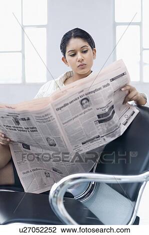 Businesswoman sitting on a chair at an airport and reading a newspaper View Large Photo Image Stock Image - Businesswoman sitting on a chair at an airport and reading a newspaper. Fotosearch