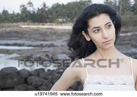 Stock Photography - Close-up of a young woman thinking on the beach. Fotosearch