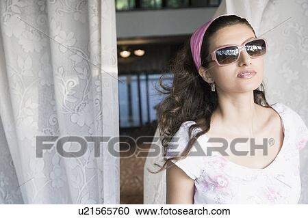 Stock Image - Close-up of a young woman wearing a pair of sunglasses. Fotosearch