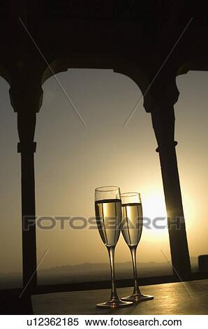 Stock Photography - Close-up of two champagne flutes under a gazebo at sunset. Fotosearch