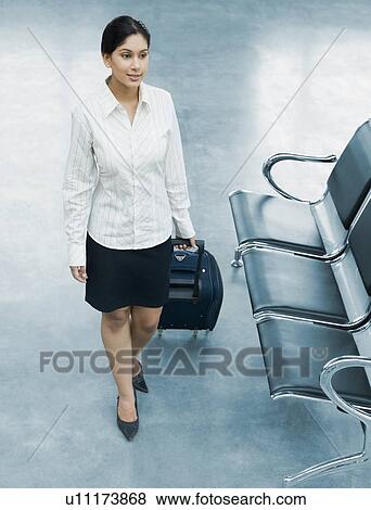 High angle view of a businesswoman pulling her luggage at an airport View Large Photo Image Stock Photo - High angle view of a businesswoman pulling her luggage at an airport. Fotosearch