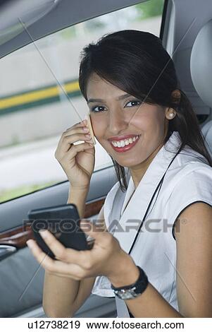 Stock Photo - Portrait of a businesswoman applying powder on her face and smiling. Fotosearch
