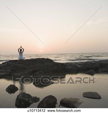 Rear view of a woman meditating on the beach View Large Photo Image Stock Image - Rear view of a woman meditating on the beach. Fotosearch