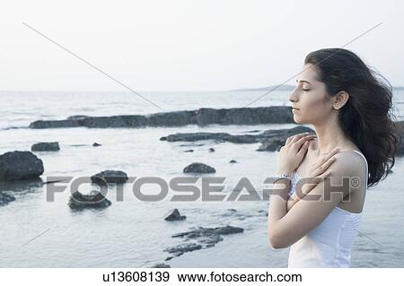 Side profile of a young woman hugging herself on the coast View Large Photo Image Stock Photo - Side profile of a young woman hugging herself on the coast. Fotosearch