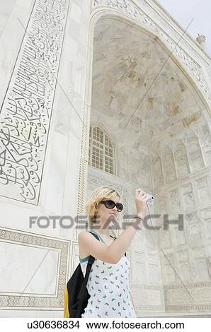 Picture - Young woman taking a picture in front of a mausoleum, Taj Mahal, Agra, Uttar Pradesh, India. Fotosearch