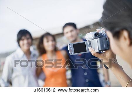 Close-up of a woman taking a video of her three friends View Large Photo Image Stock Image - Close-up of a woman taking a video of her three friends. Fotosearch