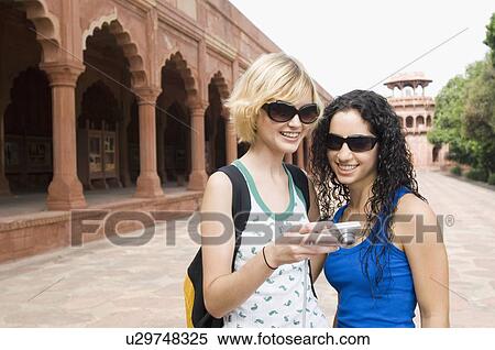 Stock Photography - Close-up of two young women looking at a digital camera, Taj Mahal, Agra, Uttar Pradesh, India. Fotosearch