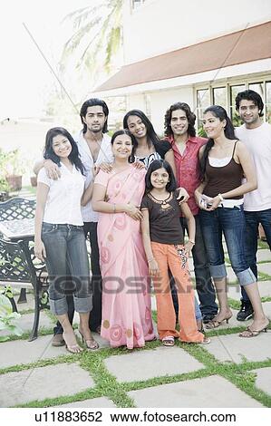 Stock Image - Mature woman standing with her daughters and her guests in front of a building. Fotosearch
