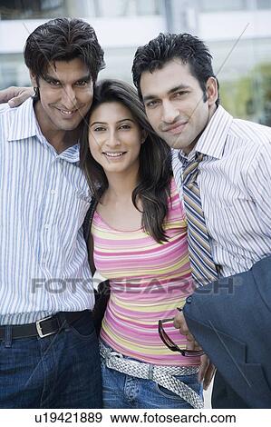 Stock Photo - Portrait of a young woman standing between two young men. Fotosearch