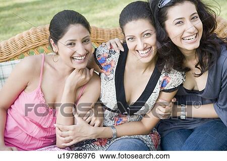 Portrait of three young women sitting together on a couch and smiling View Large Photo Image Stock Photograph - Portrait of three young women sitting together on a couch and smiling. Fotosearch
