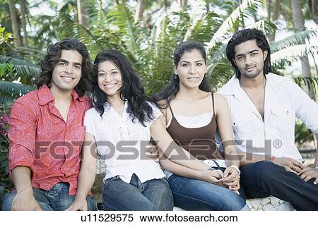 Portrait of two young couples sitting on a ledge and smiling View Large Photo Image Stock Photography - Portrait of two young couples sitting on a ledge and smiling. Fotosearch
