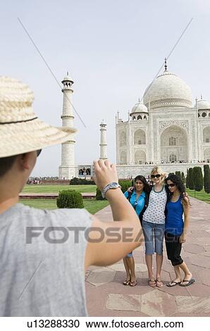 Rear view of a young man taking a picture of three young women, Taj Mahal, Agra, Uttar Pradesh, India View Large Photo Image Stock Image - Rear view of a young man taking a picture of three young women, Taj Mahal, Agra, Uttar Pradesh, India. Fotosearch
