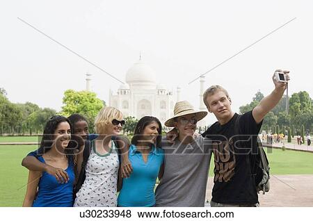 Stock Photo - Three young couples taking a picture of themselves in front of a mausoleum, Taj Mahal, Agra, Uttar Pradesh, India. Fotosearch