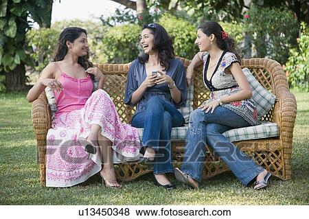 Three young women gossiping in a lawn View Large Photo Image Stock Photo - Three young women gossiping in a lawn. Fotosearch
