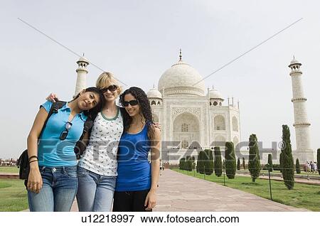Stock Photo - Three young women standing in front of a mausoleum, Taj Mahal, Agra, Uttar Pradesh, India. Fotosearch