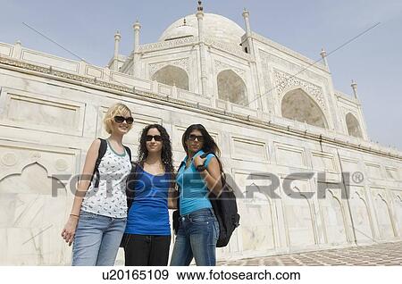 Stock Photo - Three young women standing together in front of a mausoleum, Taj Mahal, Agra, Uttar Pradesh, India. Fotosearch