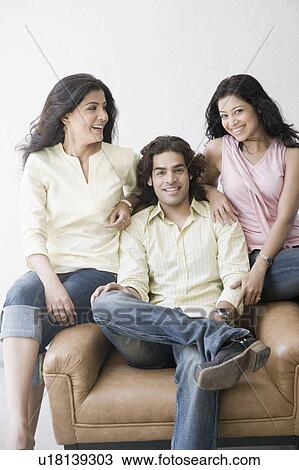 Stock Image - Two young women and a young man sitting together and smiling. Fotosearch