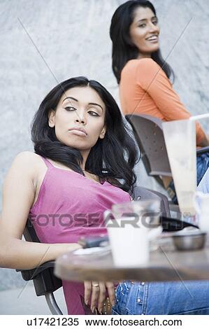 Two young women sitting in a restaurant View Large Photo Image Stock Photography - Two young women sitting in a restaurant. Fotosearch