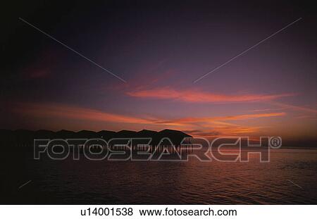 Stock Photo - The Silhouette Of The Setting Sun And The Cottage. Fotosearch