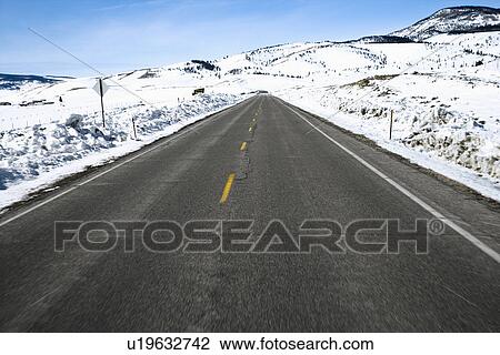 Stock Image - Perspective shot of road in snowy Colorado during winter.. Fotosearch