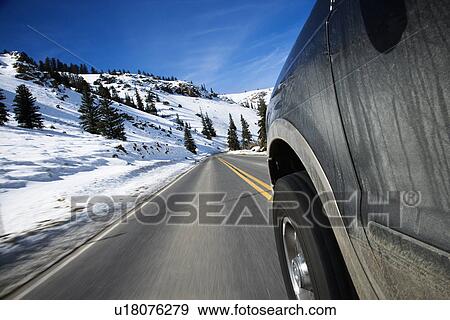 Stock Photo - Perspective shot of SUV driving down road in snowy Colorado during winter.. Fotosearch