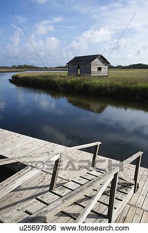Stock Photograph - Walkway down to dock on creek with weathered building.. Fotosearch