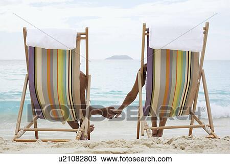 Couple on lounge chairs, holding hands (rear view), St. John, US Virgin Islands, USA View Large Photo Image Stock Image - Couple on lounge chairs, holding hands (rear view), St. John, US Virgin Islands, USA. Fotosearch