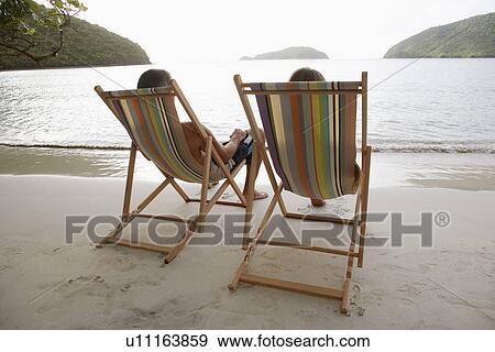 Mid adult couple on lounge chairs on beach, St. John, US Virgin Islands, USA View Large Photo Image Stock Photo - Mid adult couple on lounge chairs on beach, St. John, US Virgin Islands, USA. Fotosearch