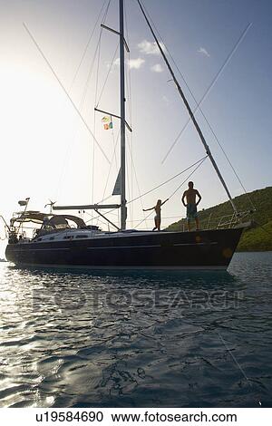 Stock Image - Mid adult couple on sailboat. Fotosearch