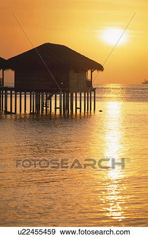 Stock Photo - The Silhouette Of The Setting Sun And The Cottage. Fotosearch